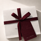 White gift box with a red ribbon and tag on a light background