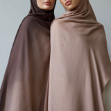 Two women wearing hijabs standing side by side against a plain background
