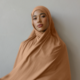 Person wearing a brown hijab against a plain background