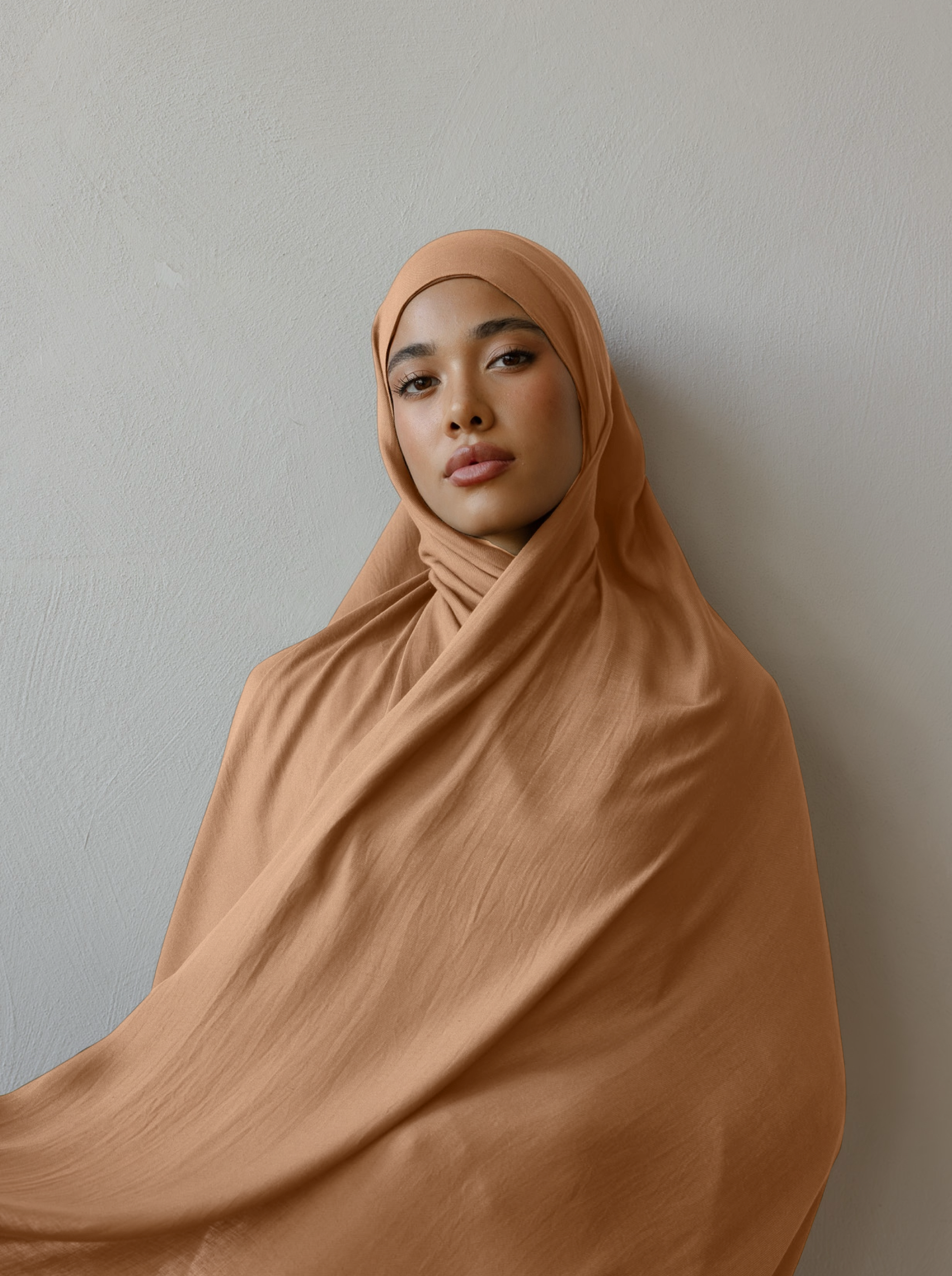 Person wearing a brown hijab against a plain background